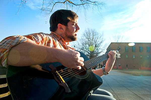 Student playing guitar on Drill Field