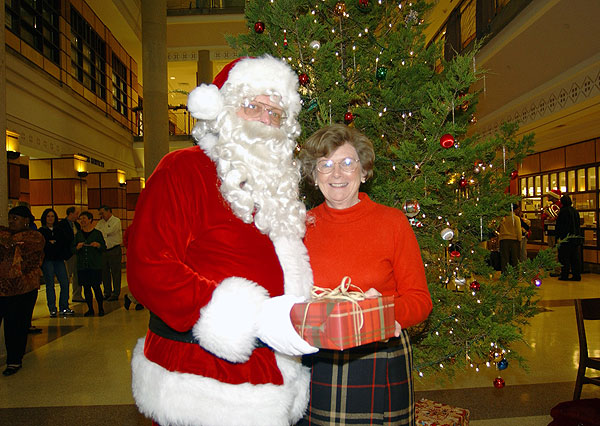 Santa and Mrs. Lee in front of library Christmas tree