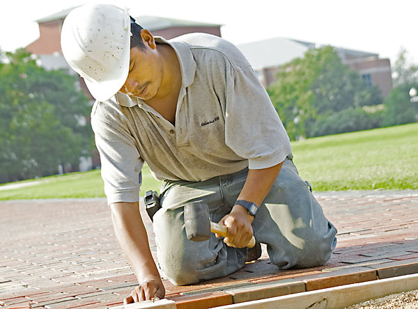 Worker sets brick in walkway