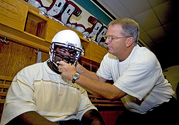 Football player tries on helmet