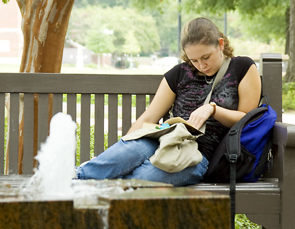 student reads by fountain