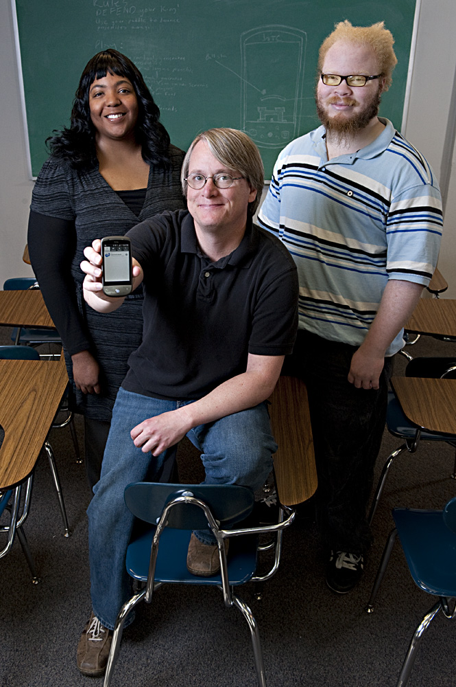 MSU students John van der Zwaag (front), Natasha Pittman and Keni Steward with the phone they use to test the game they developed.