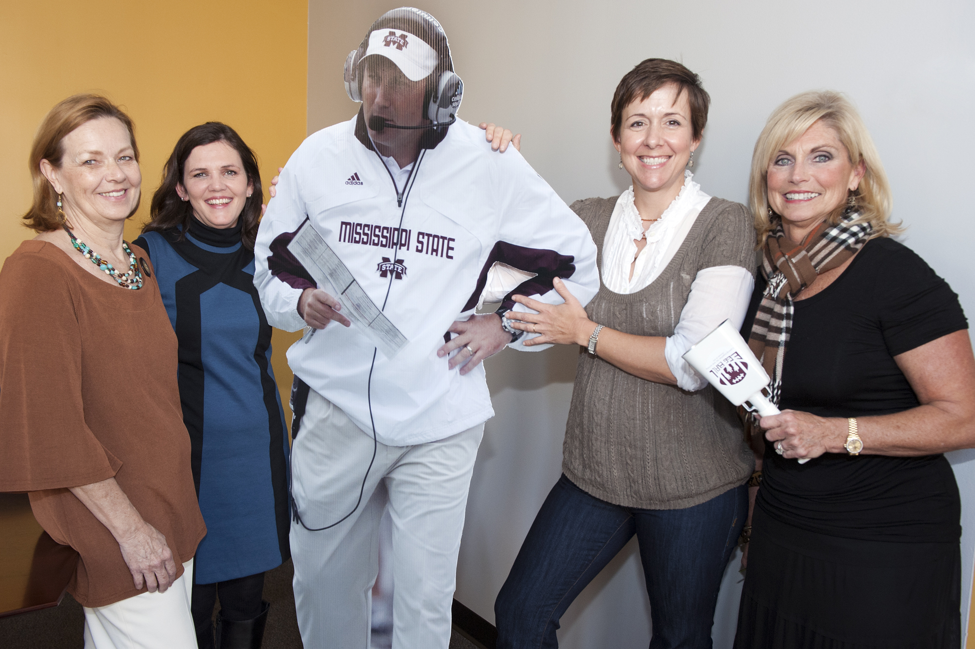 Committee members for the first Mississippi KIDS COUNT Egg Ball hope they get a "larger than life" auction bid on this life-size cutout of MSU Coach Dan Mullen during the event Nov. 26 at 8 p.m. in the Club Level of Davis Wade Stadium. Shown with the realistic carbon copy are, from left, Kim Stevens, Mary Beth Franklin, Nelle Cohen and Janet Mullins.