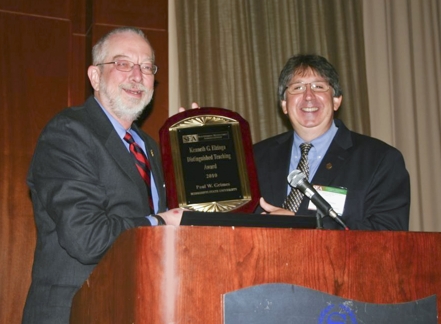 Paul Grimes, right, is presented the Southern Economic Association's Kenneth G. Elzinga Distinguished Teaching Award by the organization's president, William Shugart, a professor of economics at The University of Mississippi. 