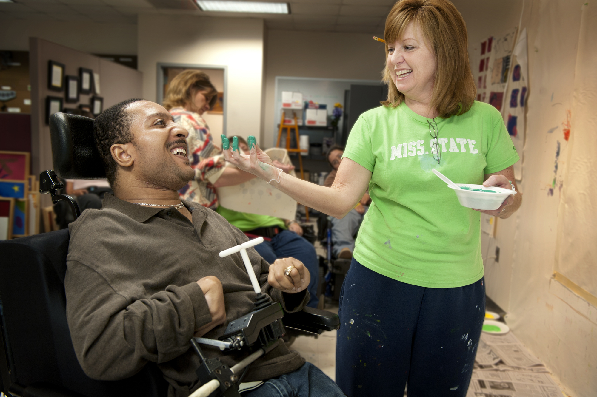 Judy Duncan of MSU's T.K. Martin Center, works with Thalamus Brown, who has cerebral palsy, to help him paint in the EXPRESS Yourself program. 