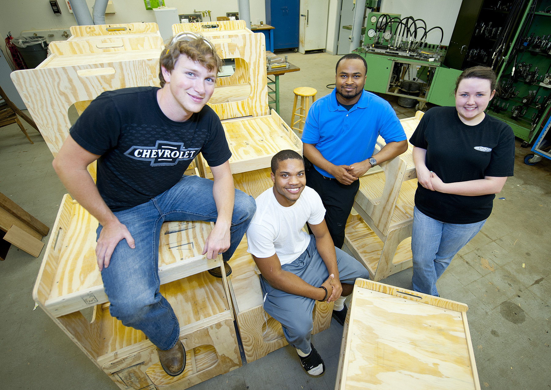 MSU industrial technology majors (front, l-r) Cory Bynum of Southaven, David Wallace of New Orleans, La., and Lara Threet of Eupora, with Polo Custom plant engineer Justin McDonald and wooden carts their class produced.