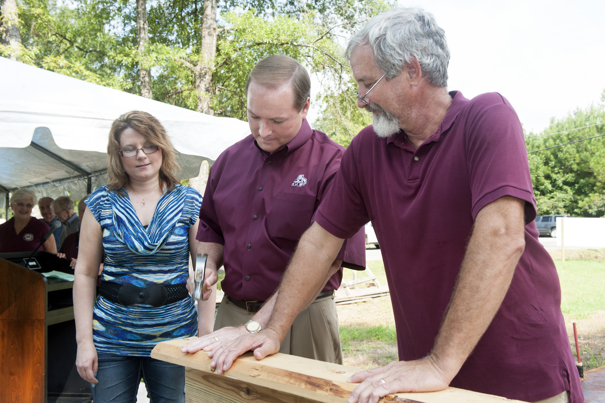 John Breazeale (r) helps MSU President Mark E. Keenum drive the first construction nail of Daphne Walton's (l) Habitat for Humanity-sponsored home.