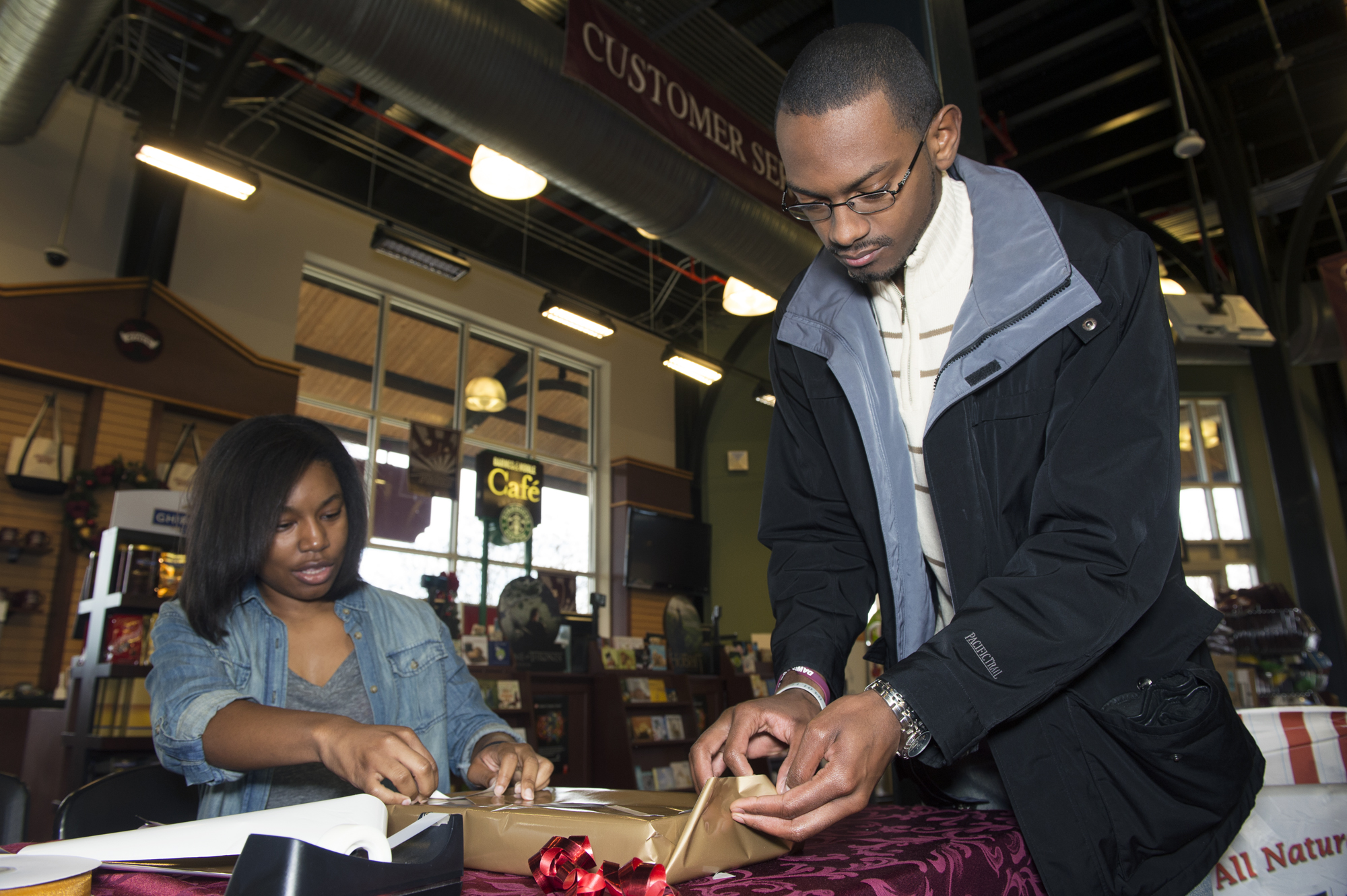 Fredricka Brown, Maroon Volunteer Center service leader, and Christopher Ferrell, MVC graduate assistant, wrap a gift as part of the Wrap a Gift Project, launched by MSU's Habitat for Humanity student organization. 