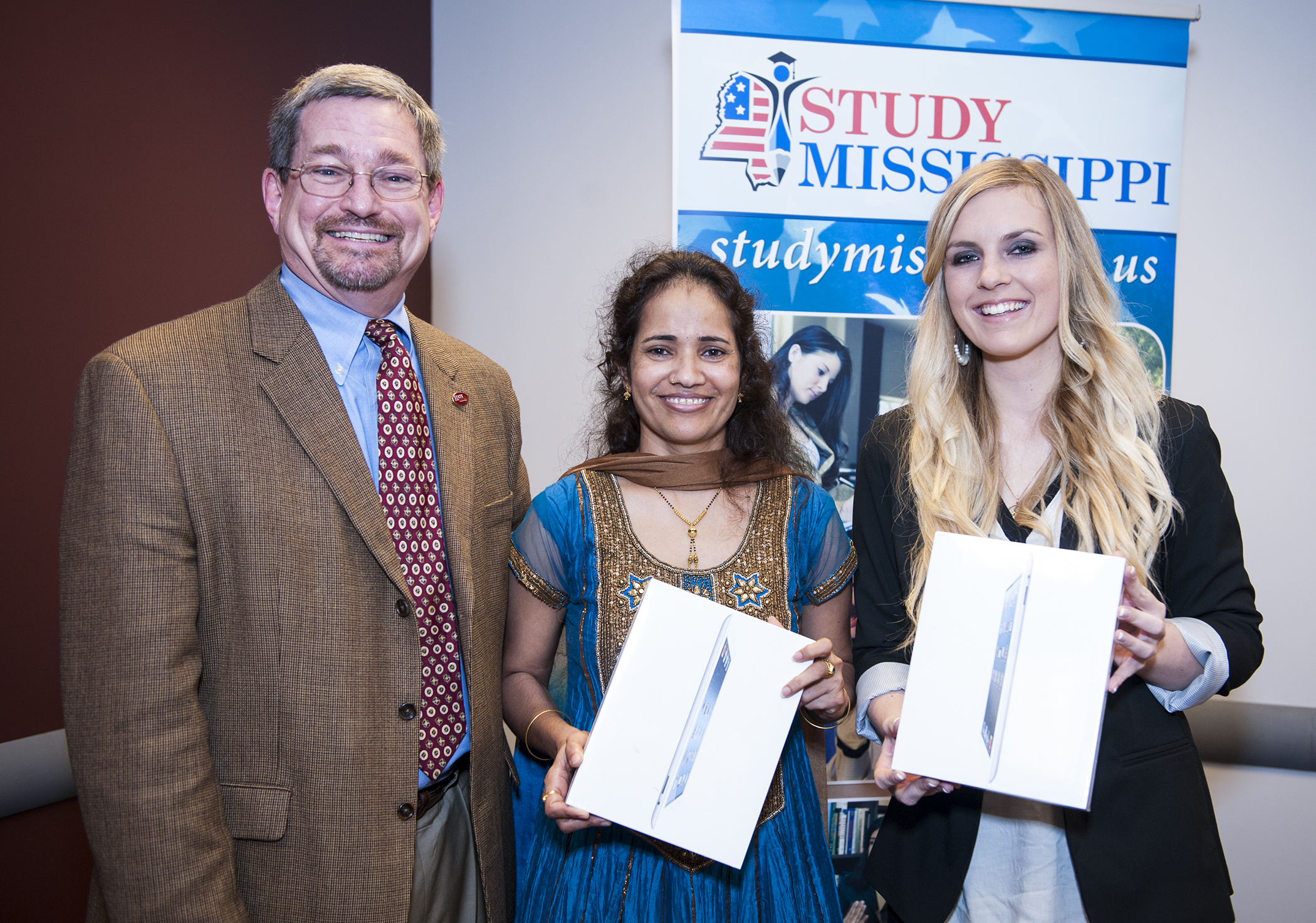 MSU International Institute Director Benjy Mikel, from left,  congratulates Aparna Krishnavajhala of India and Katja Walter of Germany for their honors as StudyMississippi Students of the Year. Both honorees received iPads at a reception in their honor.