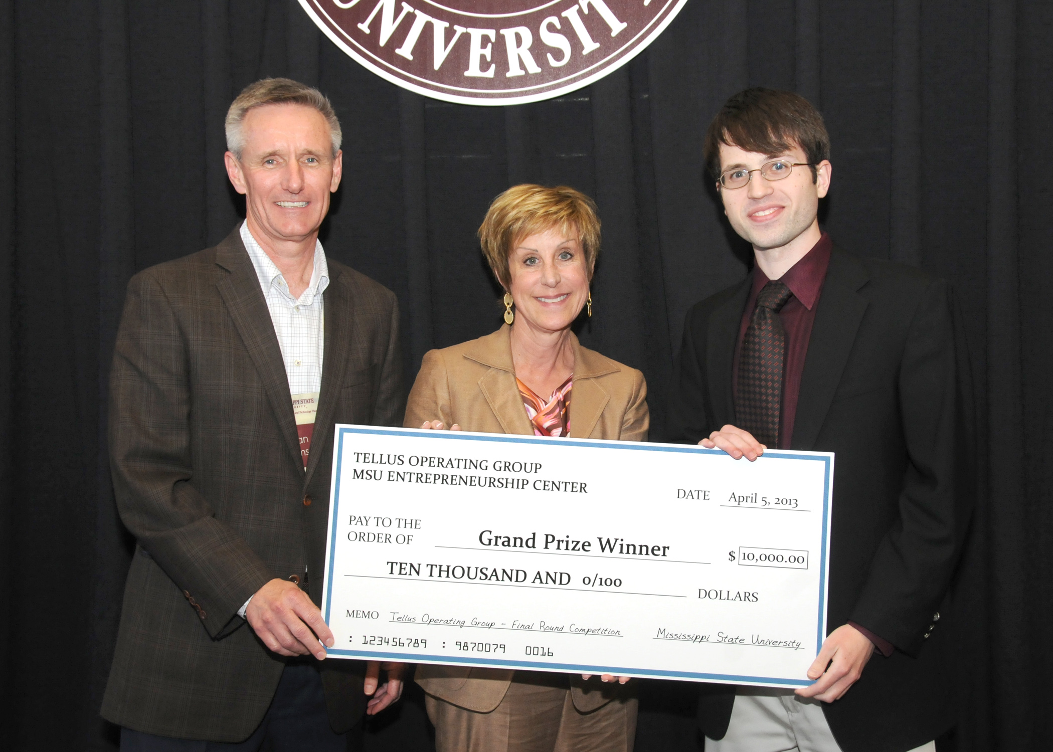 Brian Sims, from left, representing Tellus Operating Group, LLC, and MSU Dean of Business Sharon Oswald, present the grand prize award check for the final business plan competition to Read Sprabery, representing Nimbus Mobile.