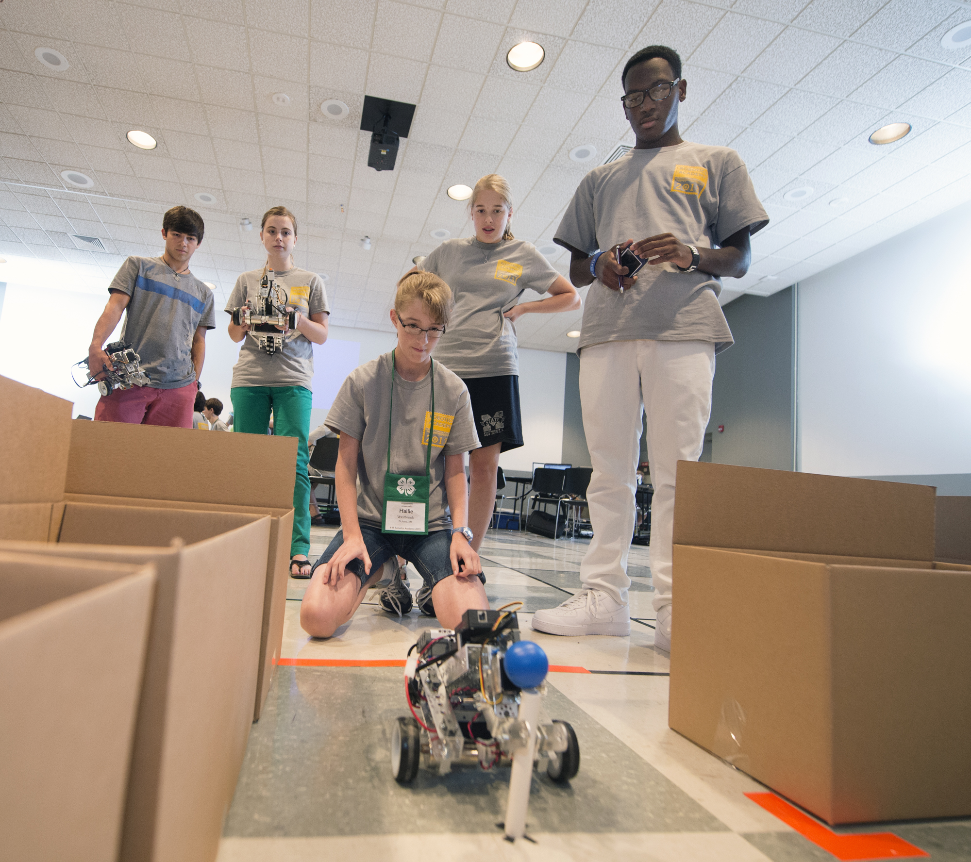 Young adults from all over Mississippi participated in MSU's first-ever, week-long 4-H Robotics Academy. Kneeling, Hallie Westbrook, daughter of Dawn and Rolan Westbrook of Pickens, tests the robot she programmed using the ROBOTC language.<br /><br />
