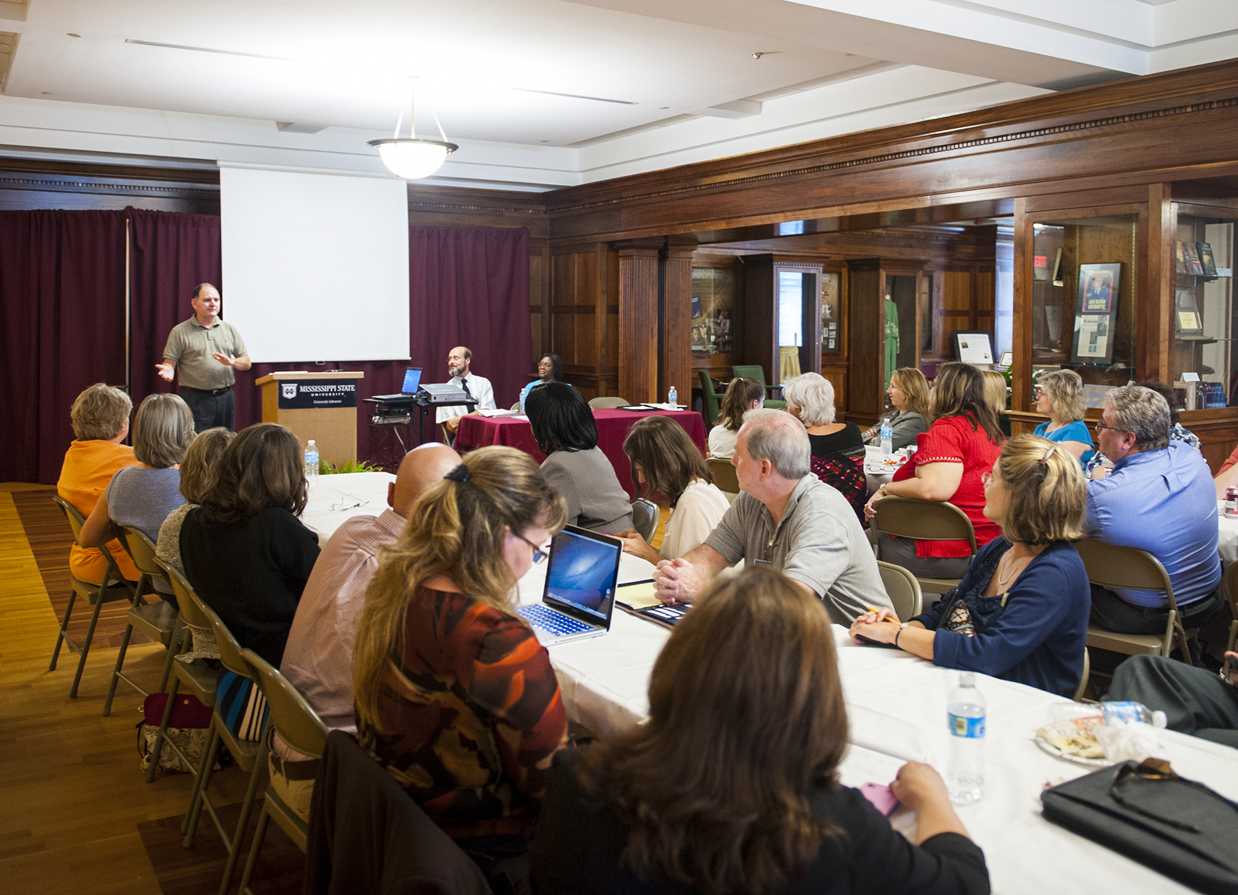 Mississippi State marketing, quantitative analysis and business law professor Robert Moore, standing, explains the university's quality enhancement plan "Maroon & Write" to colleagues at a recent luncheon. 