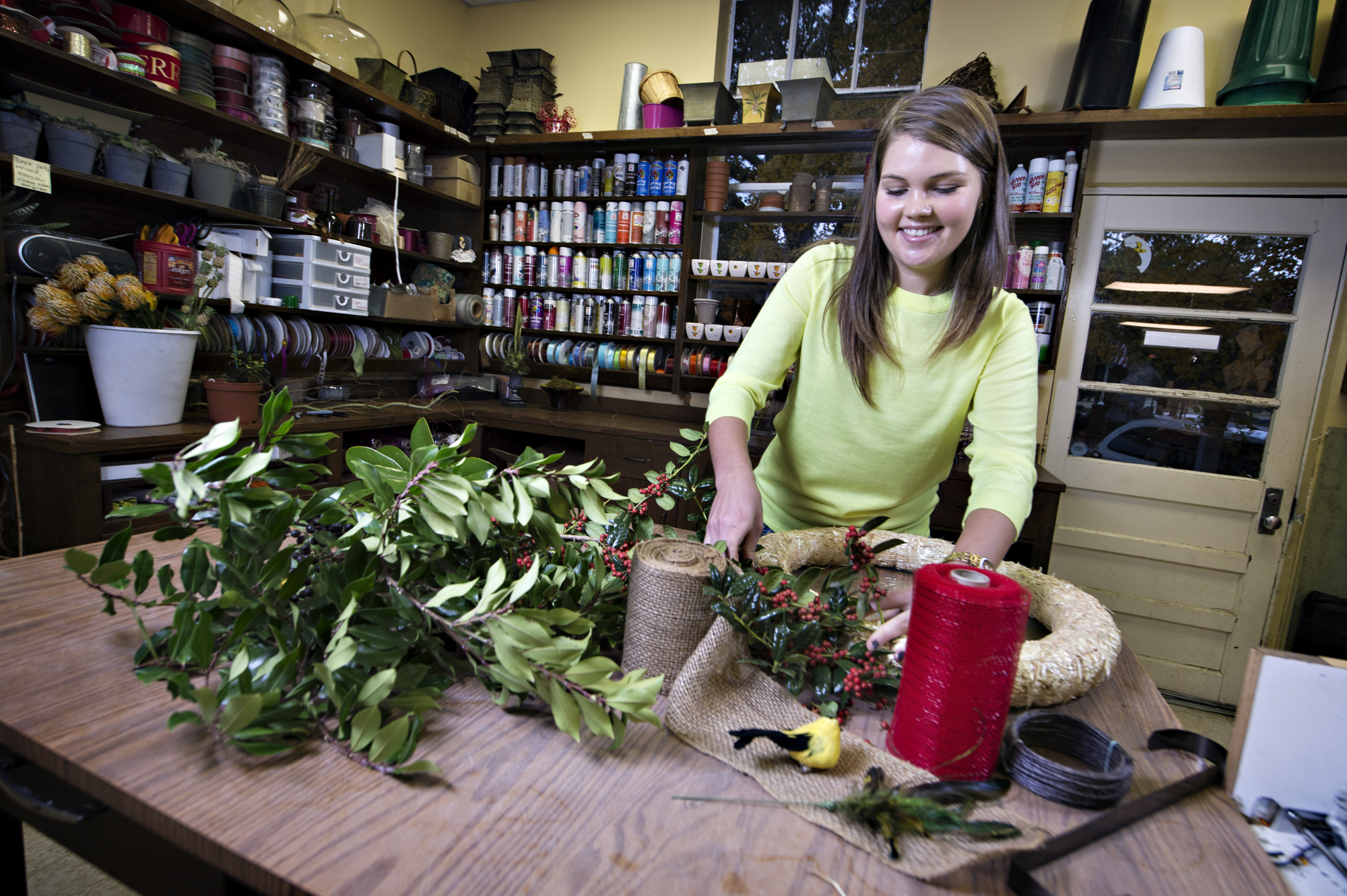 MSU junior Darby Dillard, vice president of the student chapter of the American Institute of Floral Designers, prepares an evergreen wreath at the University Florist.