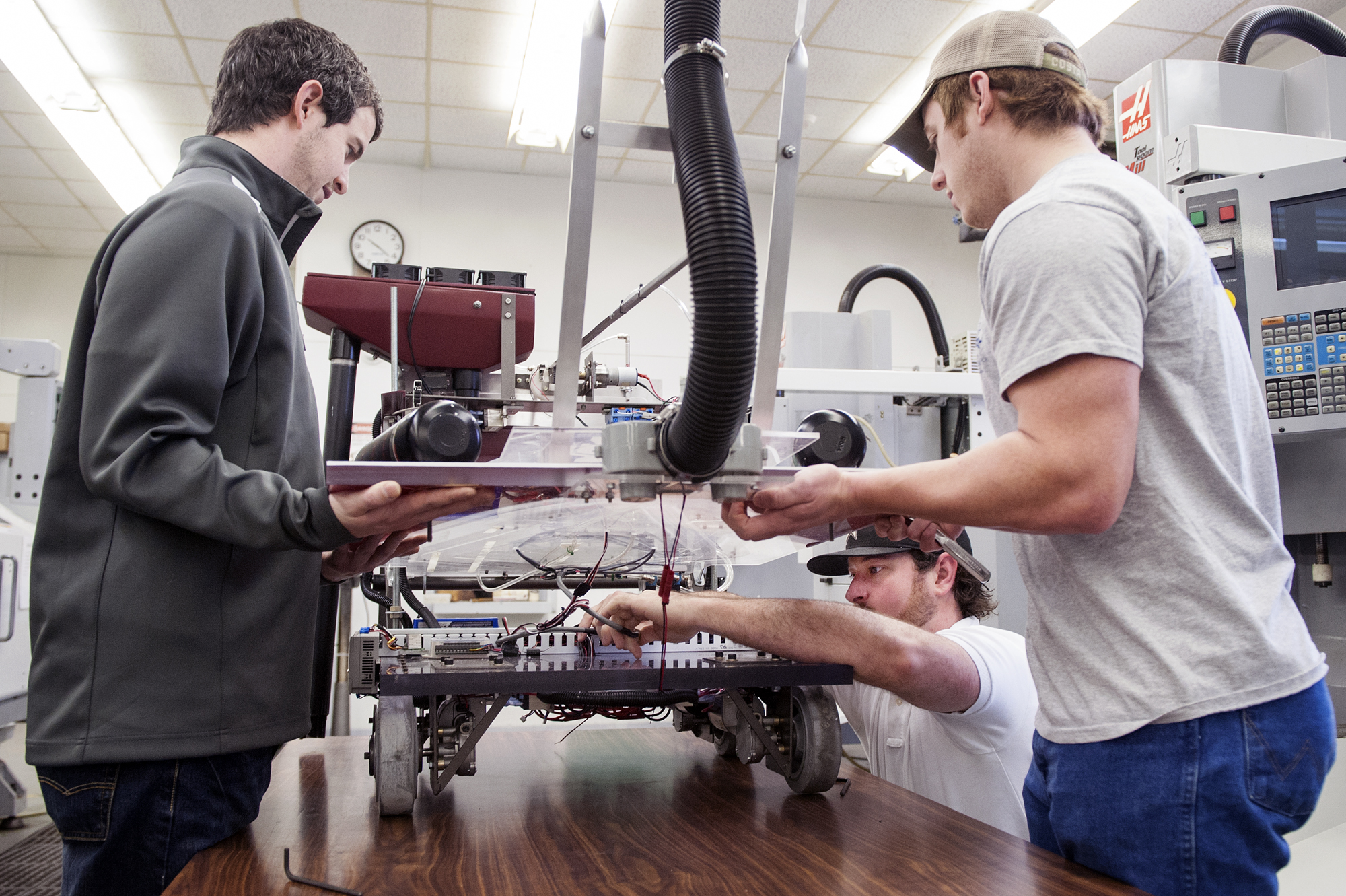 Mississippi State industrial technology students won top awards in the Robotics Competition at the recent Association of Technology, Management and Applied Engineering conference. Seniors Riley Boren, left, and Josh Lyles hold up the robot for Trey Tavares to adjust wires. 