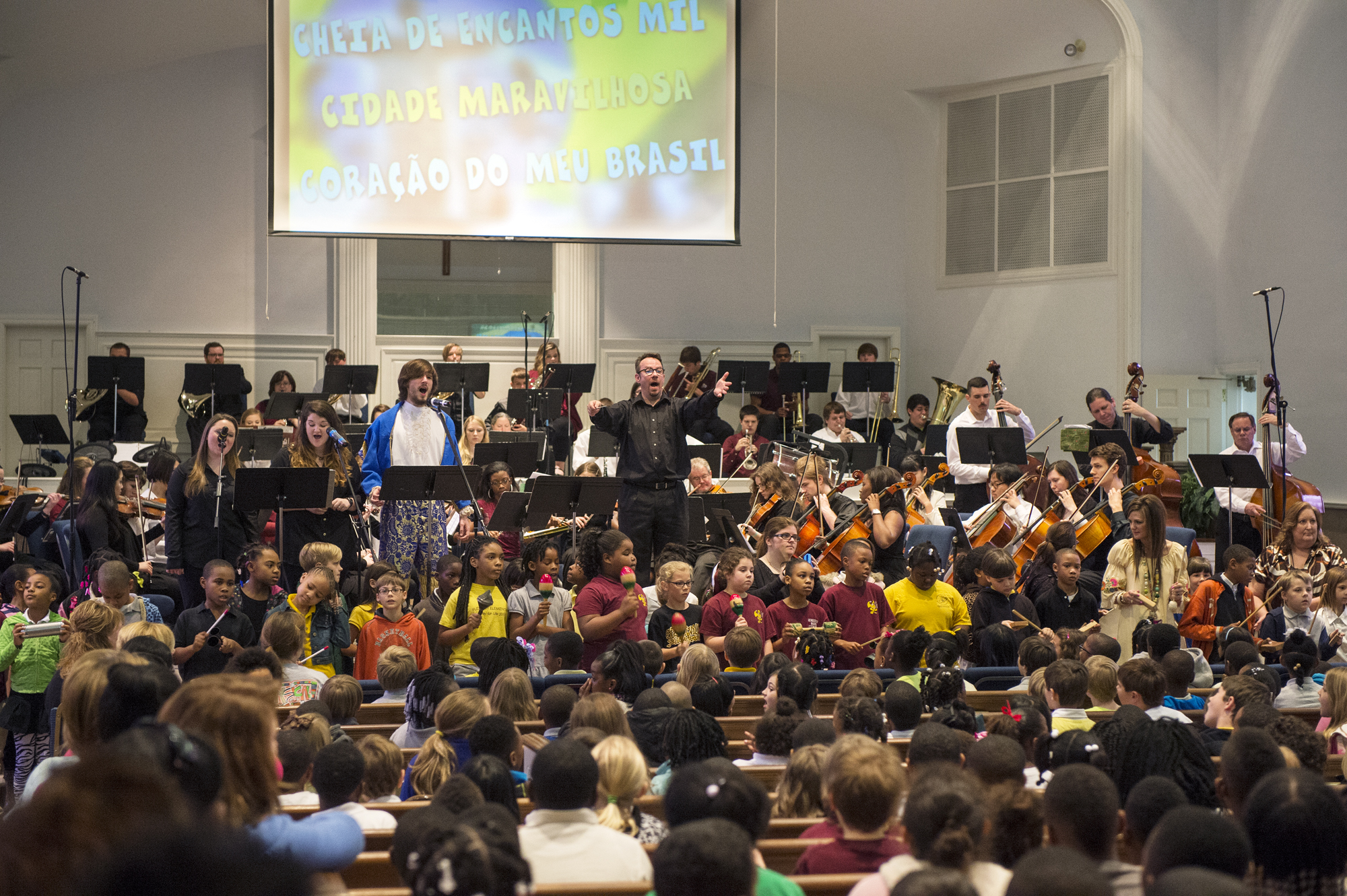 Mississippi State University Associate Professor Richard Human, center, leads local students in song during "The Orchestra Moves" event held recently at First Baptist Church in Starkville. Accompanying the students was the MSU Philharmonia, also under the direction of Human. 