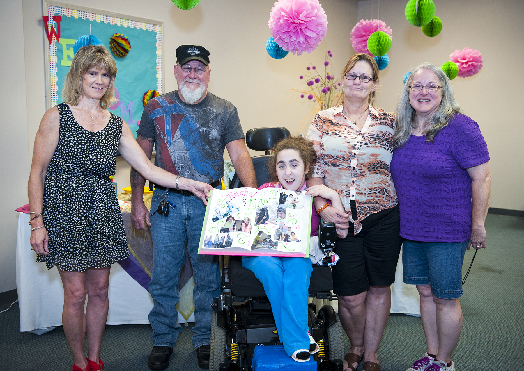 Laurie Craig (far left), speech-language pathologist at MSU's T.K. Martin Center, helps Camp Jabber Jaw participant Rachel Dickey display a special scrapbook as Earl and Sissy Barkley and mother Lisa Dickey (far right) look on.