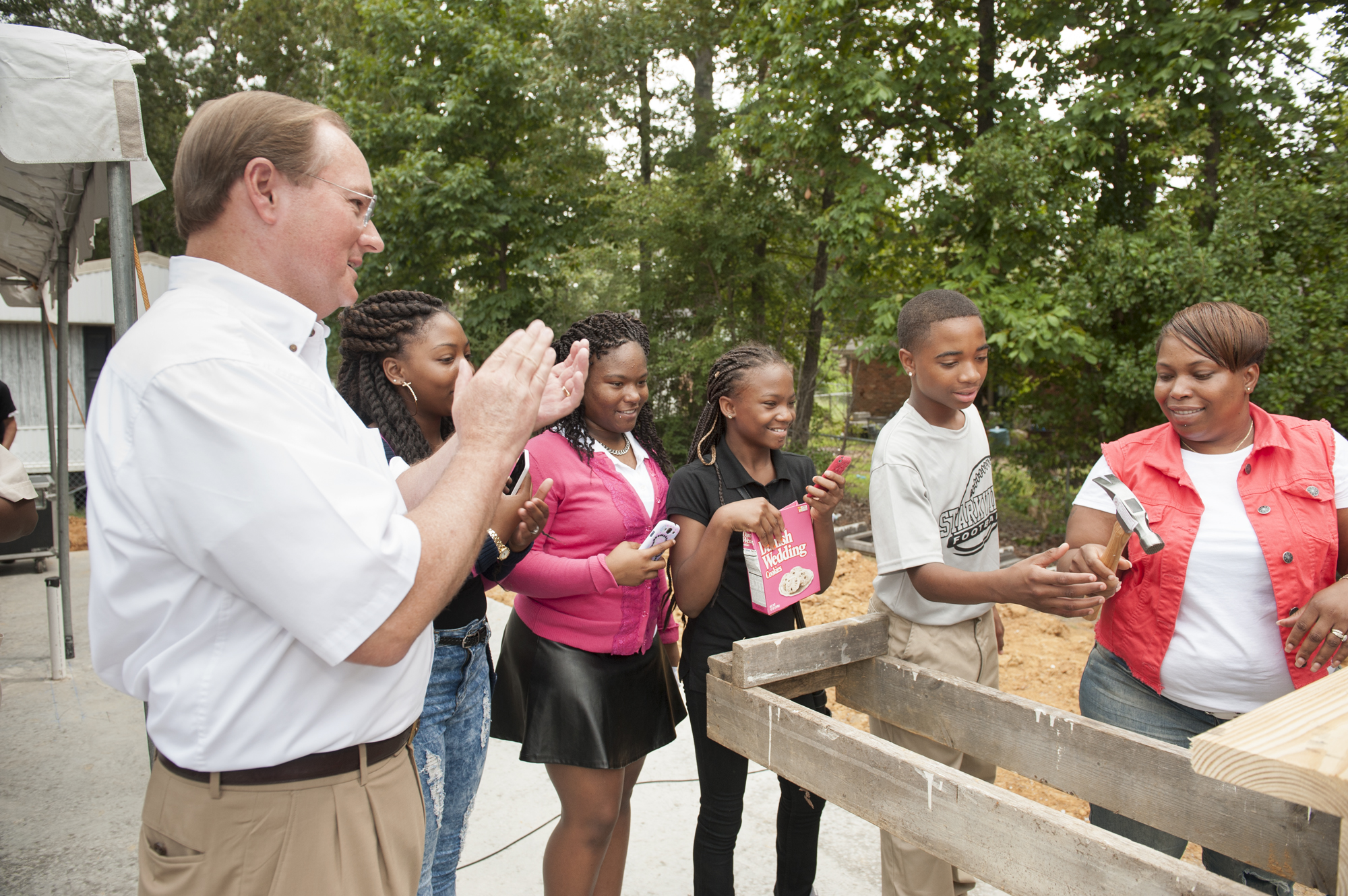 MSU President Mark E. Keenum claps as Angela Lindsey, right, passes a hammer to her son Dellveon Lindsey during the groundbreaking ceremony for the new Maroon Edition Habitat for Humanity home Monday. Looking on with Keenum are Lindsey's daughters, Lakedria Tate, Cedrianna Tate and Mya Elliott.