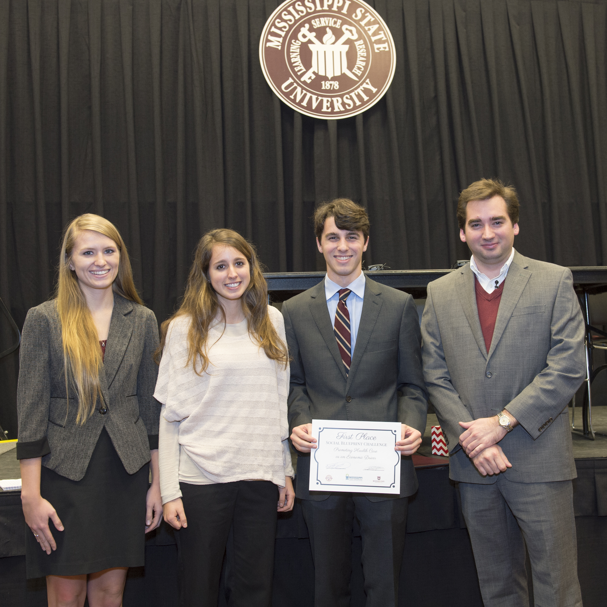 MSU's Blueprint Social Business Challenge winners (l-r) Sally White, Jamie Aron and Jack Bryan accept their first-place award from Eric Hill, program manager for MSU's Entrepreneurship Center.