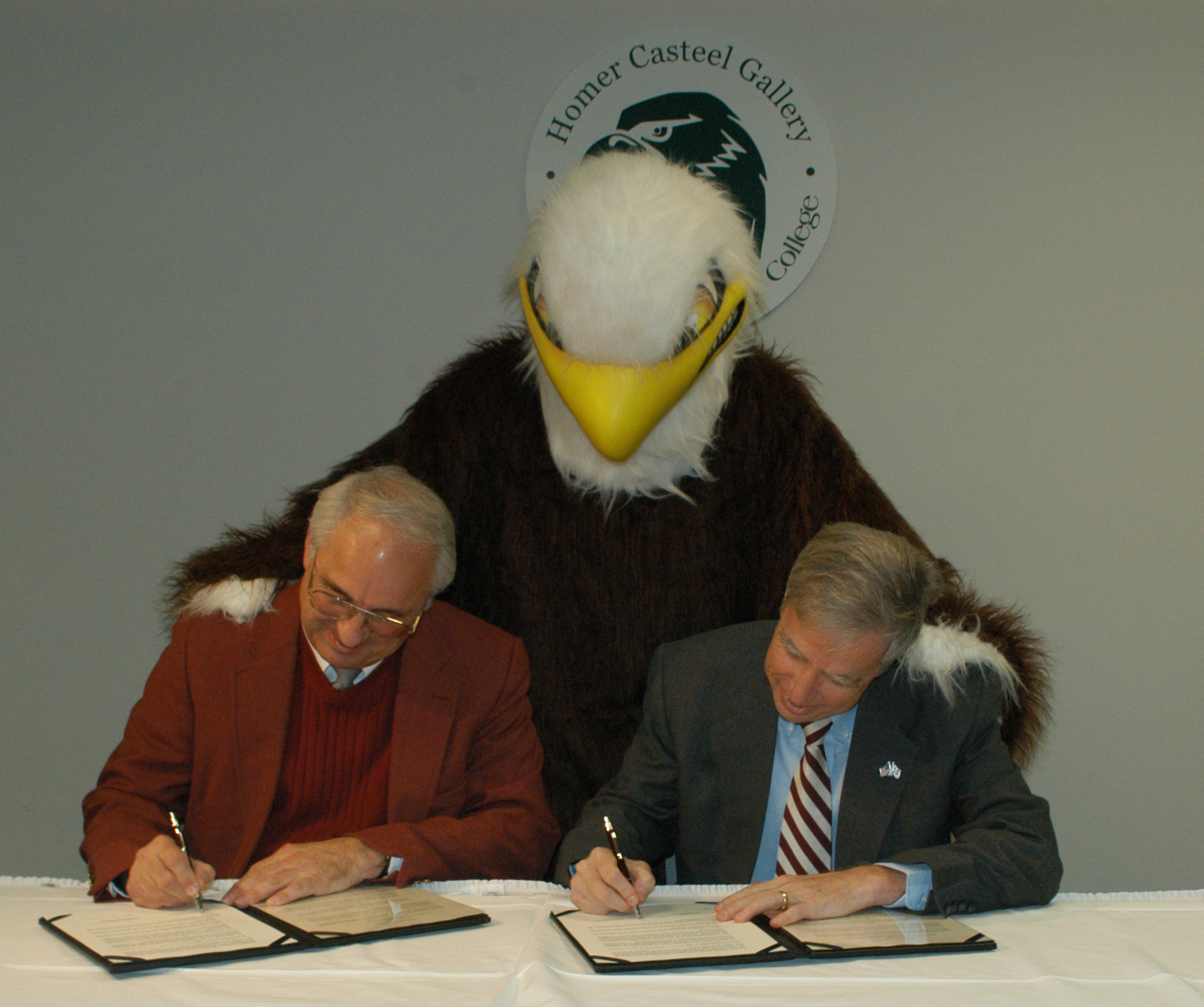 As Meridian Community College's eagle mascot looks on, presidents Scott Elliot (1) and Robert Foglesong sign the MCC-MSU agreement. 