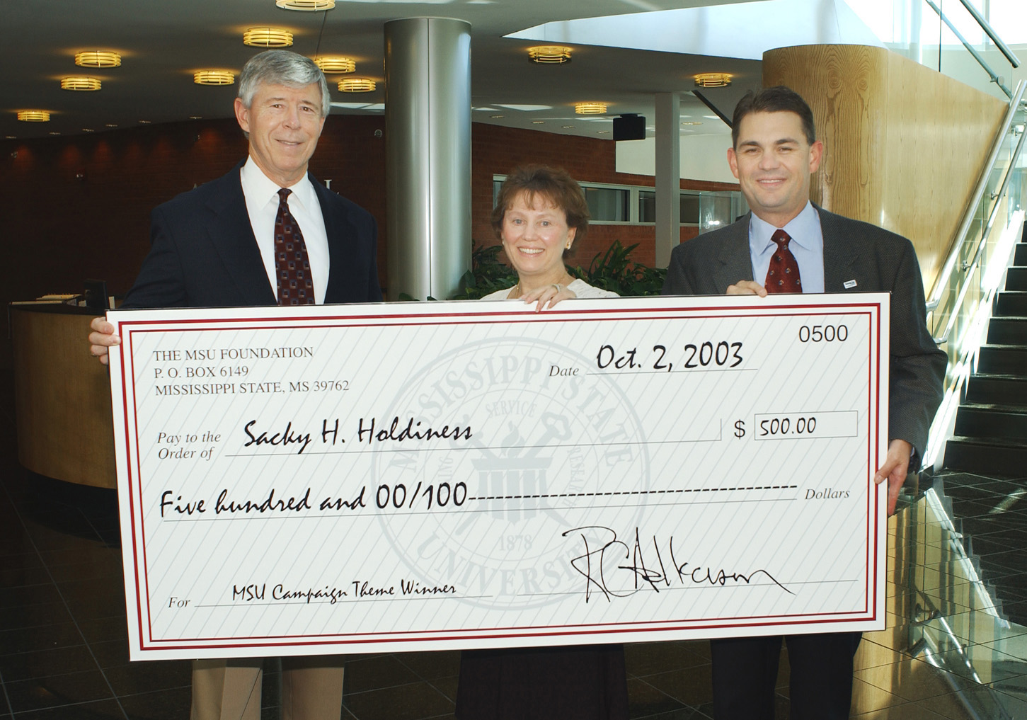 <br /><br />
Sacky Holdiness displays her $500 check with the help of MSU Foundation Executive Director Richard Armstrong (l) and Dennis Prescott, vice president for external affairs. 