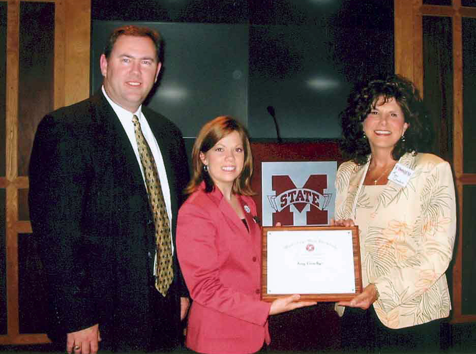 Kay Coachys (r) received the MSU award from senior Schillig Scholar Lindsay Buffum of Jackson as Oak Grove principal Wayne Folkes looked on.