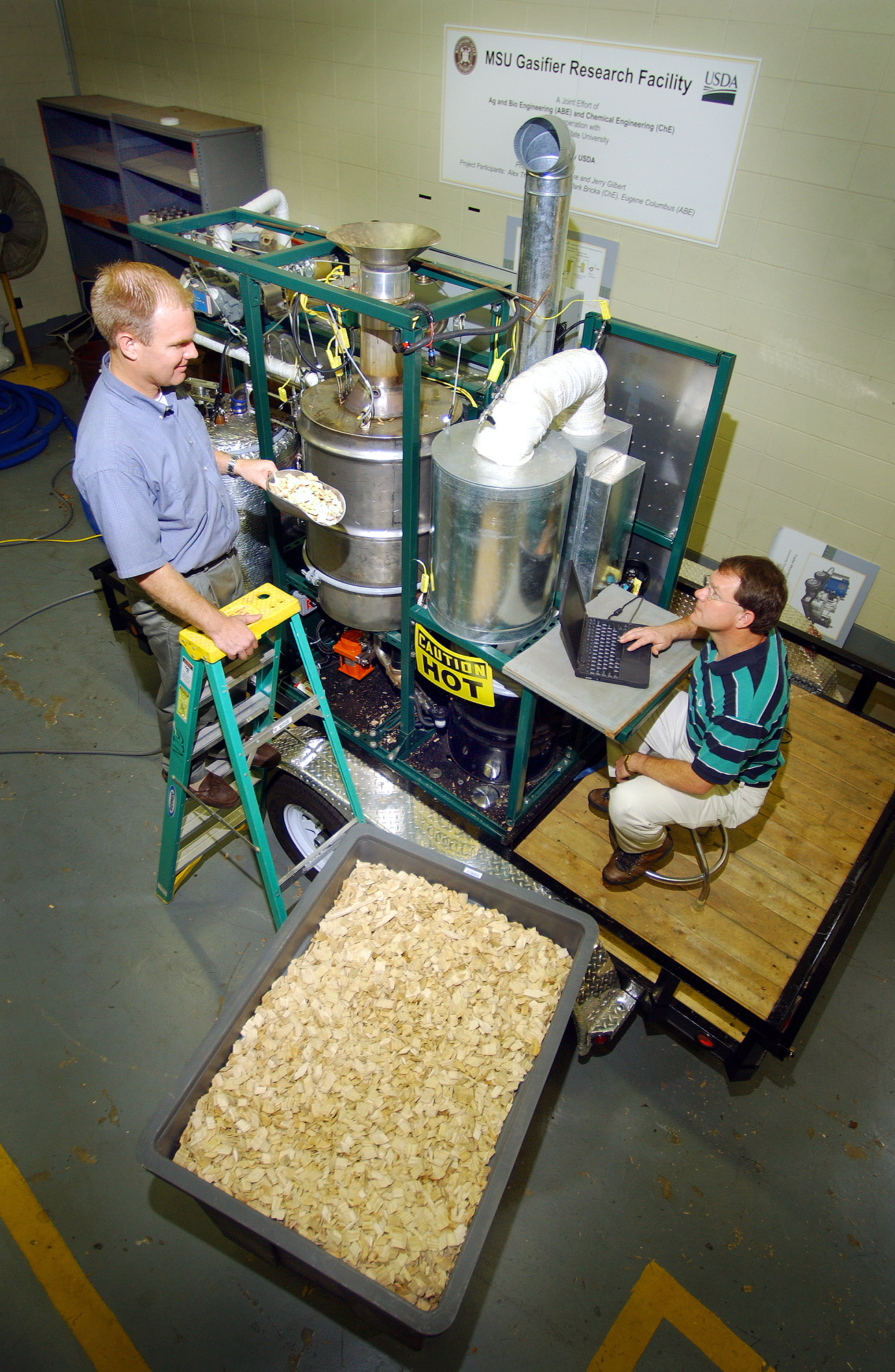 <br /><br />
Mississippi State researchers Alex Thomasson (l) and Mark Bricka feed wood<br /><br />
chips into the university's recently purchased Biomax gasifier, one of only six<br /><br />
such machines in the world. 