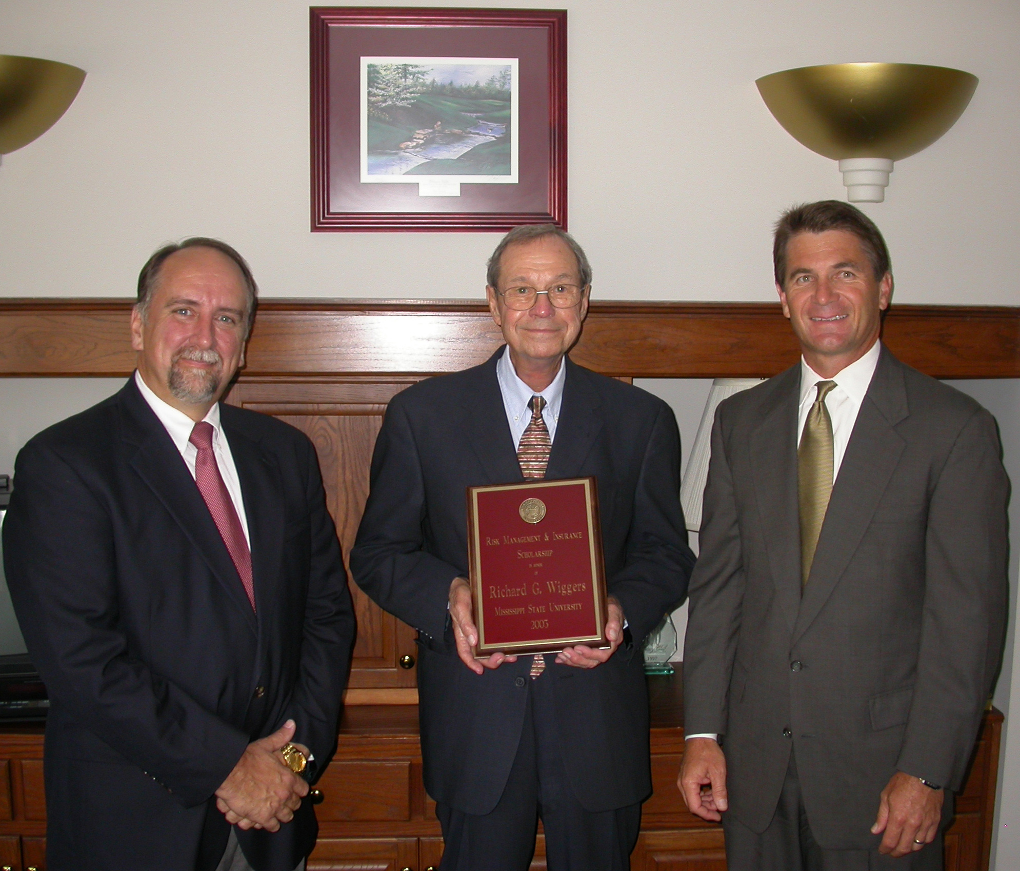 <br /><br />
Dick Wiggers (c) displays a plaque announcing the Wiggers Scholarship at MSU.  With him is former business partner James Galloway (r), who endowed the award, and Edwin Duett, holder of the university's Lutken Chair of Insurance. 